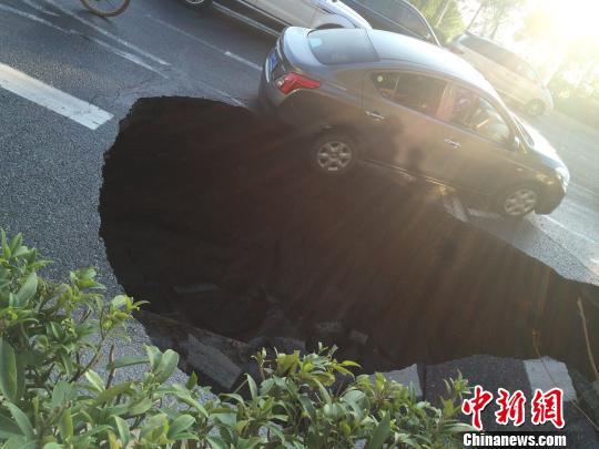 14日上午8时许，广州琶洲大桥北公交车站附近发生道路塌陷，一辆小车行驶过该路段陷入坑中。李德泽摄