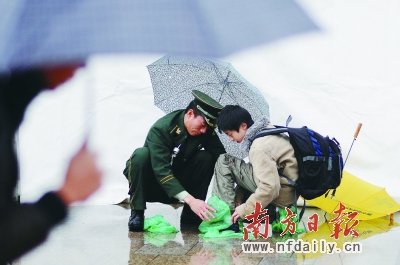 广州站武警战士雨中帮旅客穿塑料鞋套(图)
