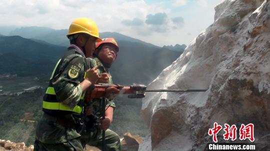 武警水电官兵在广西平乐县山体坍塌救援现场手动钻孔。李斌 摄