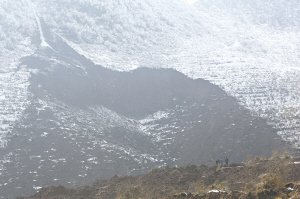 几个村民站在山脚看着山体滑坡痕迹，1月11日正是这片山体掩埋了山脚下的小村庄 都市时报记者 马闪山