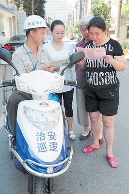 治安巡逻员向居民派送安全宣传册