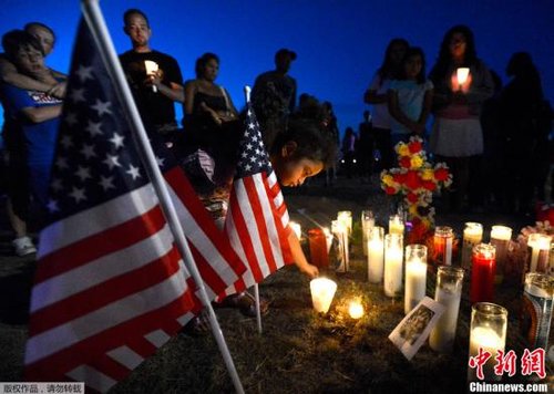 当地时间7月20日，美国科罗拉多州奥罗拉市，一位四岁的小女孩将蜡烛放置在悼念枪击案遇难者的草坪上，为遇难者守夜祈福。