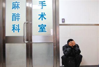 11月8日,被烫伤的京京进行第一次手术,父亲蹲在手术室外等待.