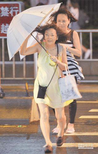 受到“鲇鱼”台风的影响，台北地区9月26日入夜之后风势转强，路人撑着伞快步越过斑马线。来源：台湾《中国时报》