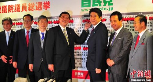 图为12月16日，自民党总裁安倍晋三（右三）和自民党高层为当选议员贴获胜标志红花。中新社发 孙冉 摄