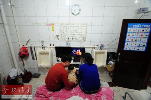 曾令军一家三口坐在电脑前看视频，电脑桌两侧就是过去悬挂的小便池（2012年3月18日摄）。新华社记者 潘昱龙摄