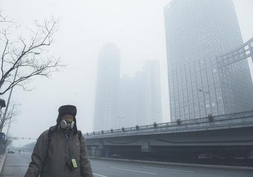 图片说明:29日,一名行人戴面具在北京的雾霾天气中出行。