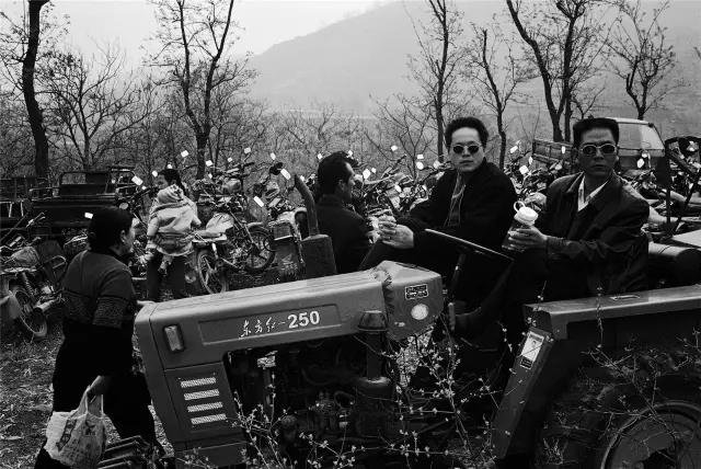 2005年4月9日,河南省偃师市。乡村庙会停车场上的拖拉机驾驶员。 2005年4月9日,河南省偃师市。乡村庙会停车场上的拖拉机驾驶员。