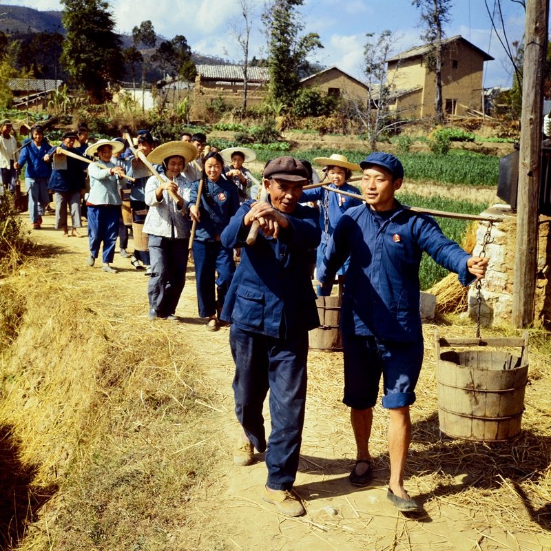 1970年,云南峨山彝族自治县,知识青年与农民一起挑着担子、扛着锄头下地劳动。 1970年,云南峨山彝族自治县,知识青年与农民一起挑着担子、扛着锄头下地劳动。