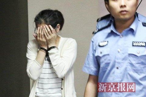 犯罪嫌疑人庞建贞双手捂脸,被法警带着准备进入法庭.