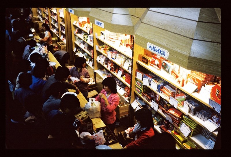 20世纪70年代末的广州,正处在改革开放的前沿,人们的视野变得开阔,想法越来越多元化。随着经济的复苏,市场变得日益活跃,票证制度、定量供给制度的取消使物质商品丰富,整个城市透出蓬勃的生机。图为拥在柜台前选购商品的顾客。 20世纪70年代末的广州,正处在改革开放的前沿,人们的视野变得开阔,想法越来越多元化。随着经济的复苏,市场变得日益活跃,票证制度、定量供给制度的取消使物质商品丰富,整个城市透出蓬勃的生机。图为拥在柜台前选购商品的顾客。
