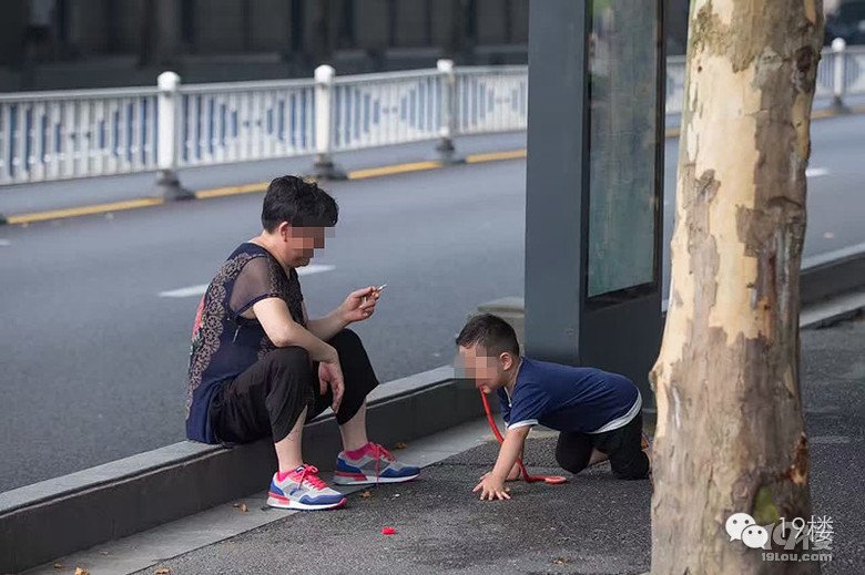 大妈当街抽烟遛孙子 让其学狗爬用嘴叼“蛇”(图)