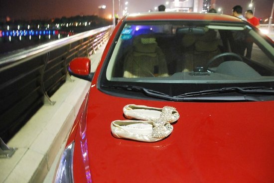 女子驾驶的红色轿车引擎盖上留有一双鞋，副驾驶座上留有便签本、手机等物。图片来自网络