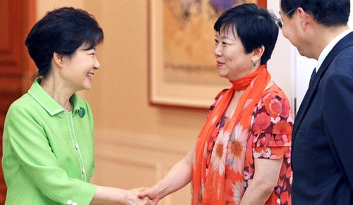 Korea president Piao Jinhui and Chinese people external Li Xiaolin of friendship association chairman (in) handclasp. Right be stationed in Korea ambassador Zhang Xin for China dark. (the picture comes from Korea " central daily " )