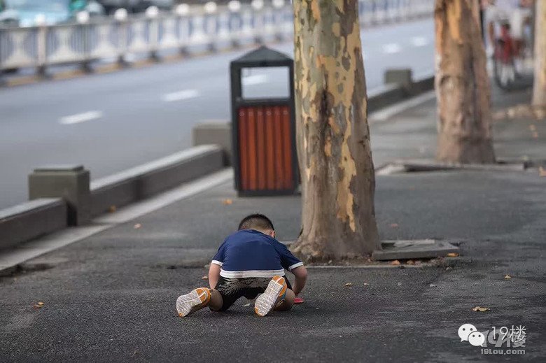 大妈当街抽烟遛孙子 让其学狗爬用嘴叼“蛇”(图)