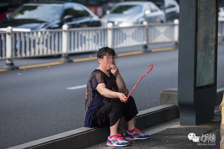 大妈当街抽烟遛孙子 让其学狗爬用嘴叼“蛇”(图)