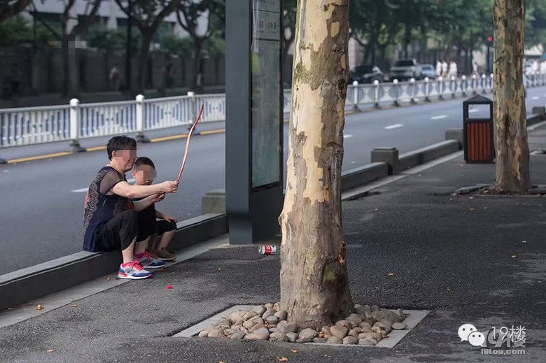 大妈当街抽烟遛孙子 让其学狗爬用嘴叼“蛇”(图)