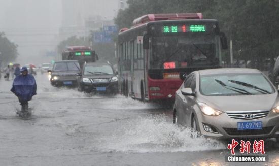 7月20日，河北省多地持续普降大雨，车辆、行人水中前行。石家庄市气象局继续发布暴雨红色预警信号和雷电红色预警信号。受雨天影响，目前市区及县区各地积水严重，多地断交，影响民众出行。图为市民雨水中出行。韩冰 摄