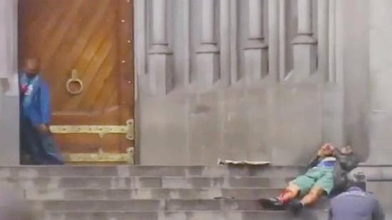 胸口流血的流浪汉靠在教堂外的柱子旁边缓缓倒地。