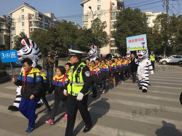 民警扮"斑马"警花跳舞 带领小学生过马路