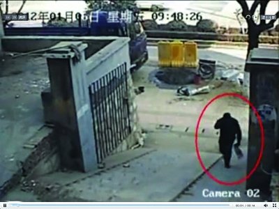 嫌疑人手拎蓝色纸袋,进入东门街小区大门。视频截图