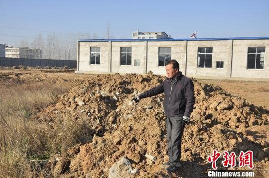 唐县镇北园村村民朱正东的土地被工厂院墙包围，耕地被“蚕食”掩埋。 吴奇勇 摄