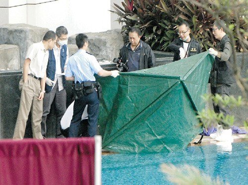 49岁妇人黄某涉斩死同居男友彭炽辉后，再从君临天下第3座77楼复式单位中一跃而下，直跌落泳池死亡，图为警方人员事后检视被抬至泳池边的尸体。 香港明报图