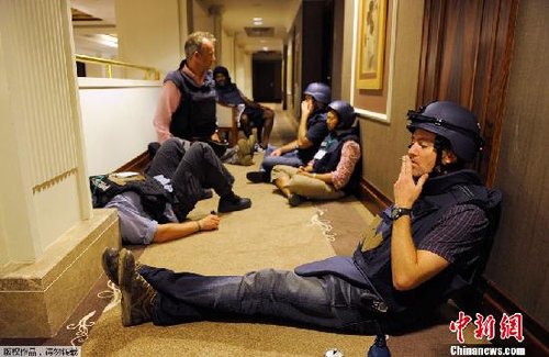 之前在卡扎菲阵营内报道利比亚冲突的30多名外国记者目前被困于利比亚政府军控制的里克索斯酒店内，其中包括5名中国记者。图为2011年8月23日，几名外国媒体记者聚集在酒店走廊里。