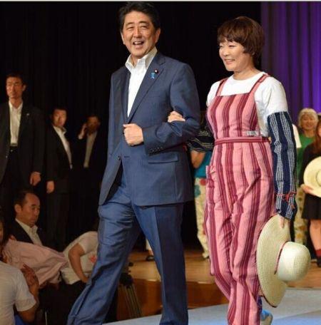 安倍昭惠身穿扎腿劳动裤，以“农家女孩”的形象同安倍手挽手同登舞台