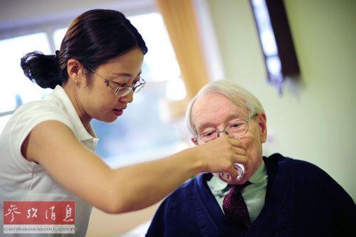 一名中国护士在德国法兰克福的养老院里给老人喝水