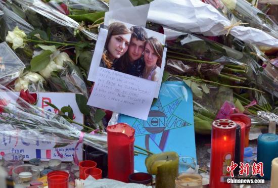 当地时间11月16日，法国举国哀悼巴黎恐怖袭击的遇难者。中午12时，全国民众默哀一分钟悼念死者。在各个遇袭地点，大批民众自发聚集鲜花燃烛表达纪念之情。这是这是《查理周刊》血案后不到一年时间内，法国第二次行国殇之礼。图为巴黎11区巴塔克兰剧院附近的纪念场所摆放着遇难者的遗照。 龙剑武 摄