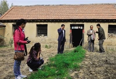 10月15日，高密市莫言旧居前，男子向管谟欣赠送窗帘。最近常有做企业的和自称搞文化产业的人找他谈合作事项，管谟欣都没有应允。院中萝卜地里的萝卜已经被来访者拔去不少。10月15日中午，山东省高密市大栏乡平安庄，30多个慕名从东营市、大连市，以及韩国的来访者，穿过敞开的铁门，来到莫言二哥管谟欣家满是金黄色玉米棒子的院落中。“我们是来看莫言旧居的。”声音传到屋里炕上的管谟欣耳中，他边应承边熟练地从抽屉拿起钥匙，拉开门，伸出布满老茧的手，笑吟吟地迎接大家，然后，领着大伙儿往约500米开外的莫言旧居走去。同样的动作，自莫言获诺奖后，管谟欣不知做了多少次，包括反复接受几十家中外媒体记者的采访。山东省旅游局的调研组也来到这里，考察将旧居开发成旅游线路的可行性，并提出修缮旧居。村民说，此前，莫言曾屡次婉拒当地政府的修缮请求，却自掏腰包，给村里修了路。新京报记者 陈杰 摄影报道