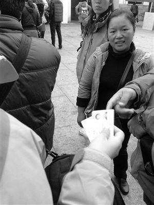 一位“黄牛”（右一）在兜售高价票，游客准备将身份证交给她