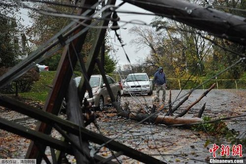 当地时间10月30日，飓风“桑迪”裹挟着狂风骤雨重创了美国东海岸，飓风所经过之处一片狼藉。图为飓风“桑迪”袭击后，美国马里兰州Chevy Chase街道上的电线杆倒塌阻断道路。 