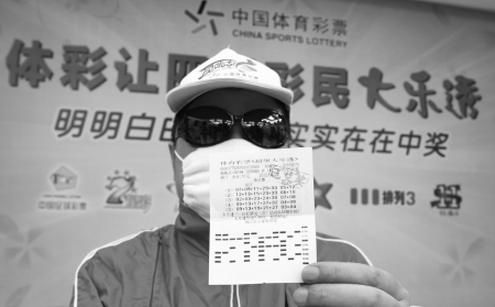 用大口罩、大墨镜,帽子全副武装的得奖者,站在“明明白白、实实在在中奖”的标语下 用大口罩、大墨镜,帽子全副武装的得奖者,站在“明明白白、实实在在中奖”的标语下