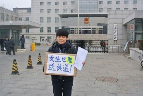 小卢在顺义区法院门前举着“女生也能送快递”的牌子