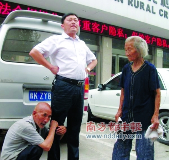 屯里村一名老大爷抱着一名男子大腿,在一处信用社建筑前讨要存款 屯里村一名老大爷抱着一名男子大腿,在一处信用社建筑前讨要存款