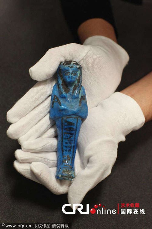 英国牛津，博物馆工作人员手拿一只精巧的"沙伯提"木乃塑像，这件展品在阿什莫尔博物馆从古埃及到努比亚工艺品展被展出。