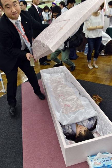 日本举行殡葬展 参观者躺棺材体验服务