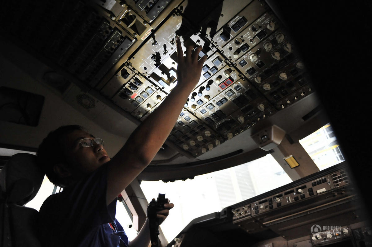徐童正在对一架飞机驾驶舱上的电子设备进行检修.