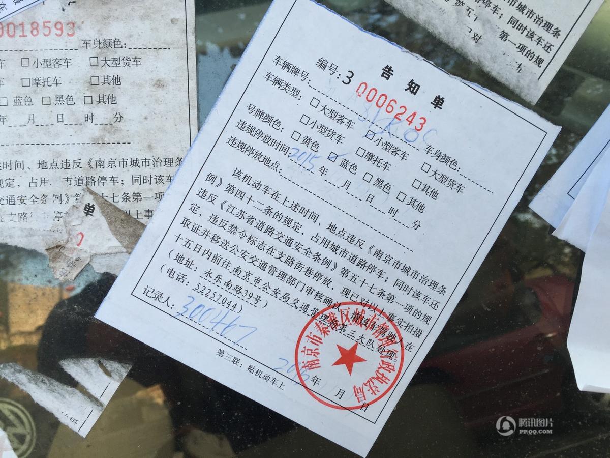 南京一轿车窗户上被贴满罚单 引围观