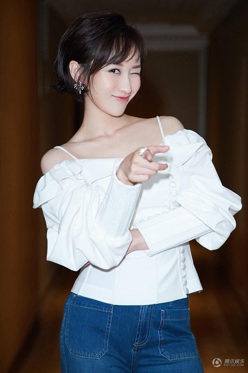 练练身穿白色一字肩白衬衣,搭配紧身喇叭牛仔裤,气质出众,优雅身姿和