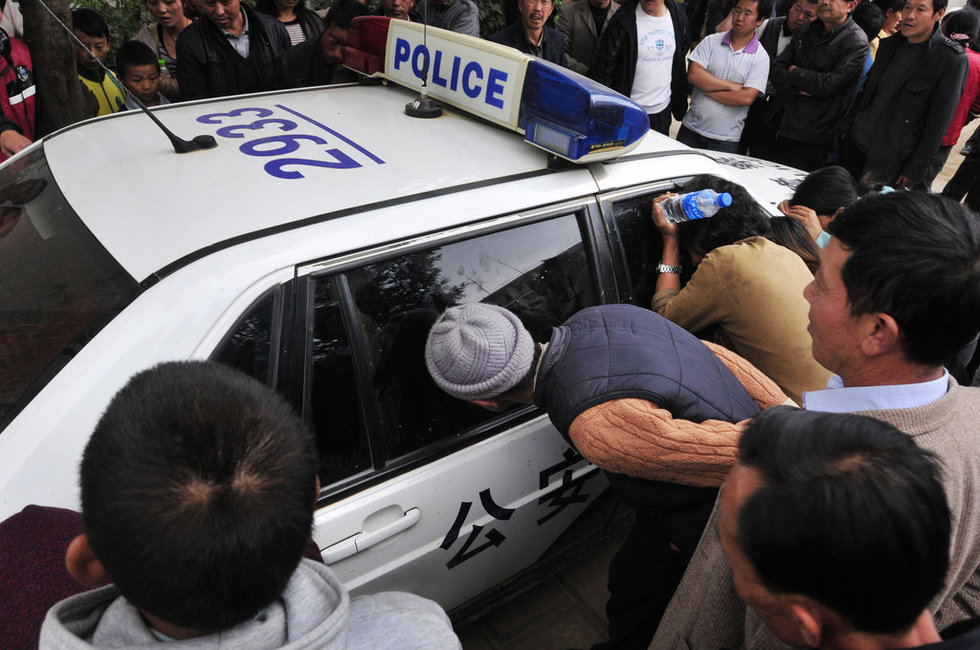 图为村民围着躲在警车上大板桥街道