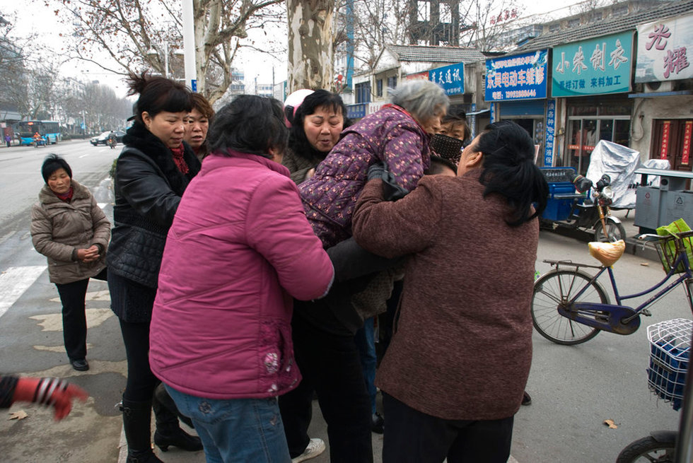 市民合力将一位患有老年痴呆而突然倒地的老人扶起背回家.