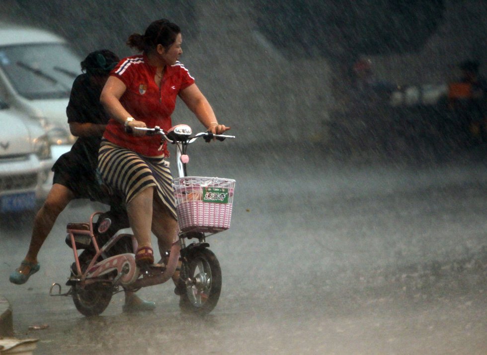 6月23日,河南洛阳,行人在狂风暴雨中艰难行进.