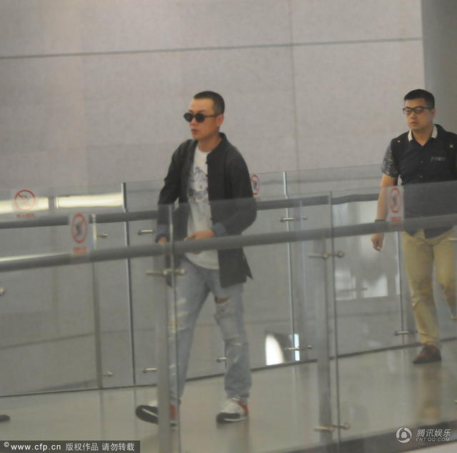组图:文章低调现身机场 独自一人抽烟解闷
