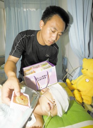 小琳的父亲拿着好心人送来的月饼,希望能唤醒女儿.本报记者 杨新宇 摄