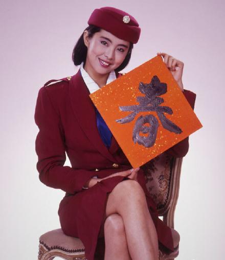 照片中,王祖贤身穿一身暗红色礼服,手持.