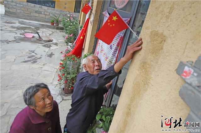 9月17日,阜平县骆驼湾村,唐宗秀老两口正在家门口插国旗.