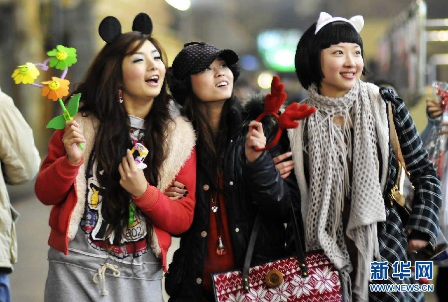 图为2008年12月24日夜,在湖北省宜昌市街头,3名个性装扮的女孩在